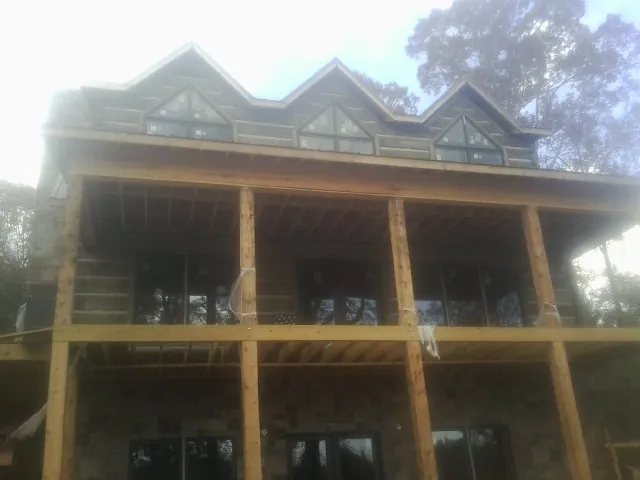 Dormers and porch framing on a large log home under construction — Roof Coating work by our crew in Nellis Afb