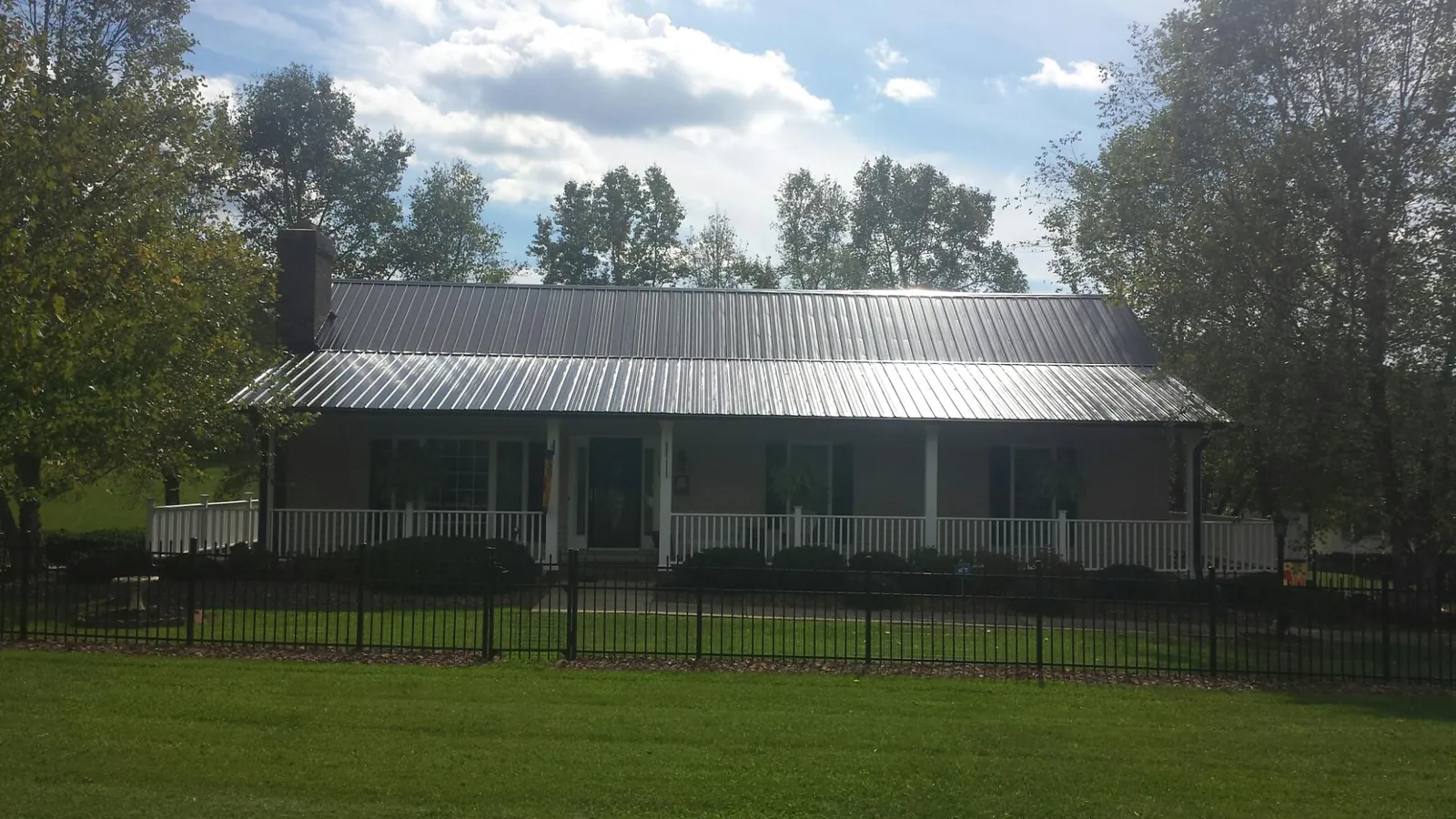 Gray metal roof on a brick ranch with a full width front porch — Gutter Guard Installation work by our crew in Nellis Afb