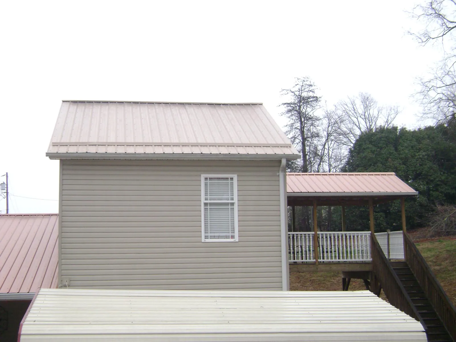 Tan metal roofs on a two story addition and attached porch, from a Roof Replacement job in Nellis Afb